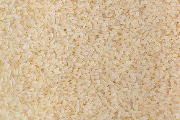 Background of uncooked parboiled white rice. Light grains, organic natural healthy food top view. Ingredient for traditional Asian cuisine. Cereal surface.