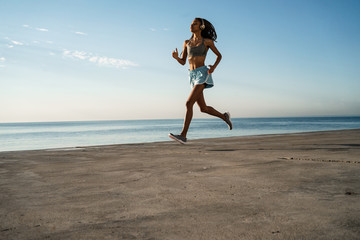 Fototapeta na wymiar Image of african american girl in headphones running on promenade