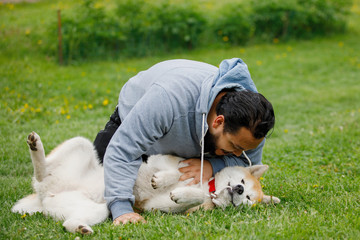 Guy with red akita dog on green grass.