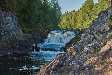 Naklejka na ściany i meble Plain waterfall Kivach.Long multistage flat waterfall. Seething waves and water falling on stones are visible. The slopes are rocky, spray and rainbow are visible. Russia, Karelia, Kivach