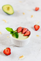 Avocado panna cotta with strawberry pieces and mint in a white bowl. Sugar, lactose, gluten free. Healthy food, diet, vegetarian.