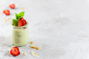 Avocado panna cotta with strawberry pieces and mint in a glass. Sugar, lactose, gluten free. Healthy food, diet, vegetarian. Horizontal orientation, copy space.