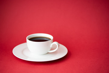 black coffee in a small coffee cup on a red background