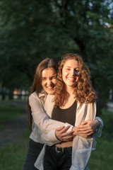 Obraz premium Two young beautiful caucasian girls laughing while walking in the park