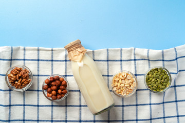 Top view of vegetable milk bottle with bowls of nuts