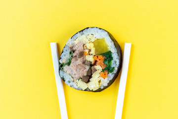 Korean rolls gimbap wooden sticks on yellow background close-up.