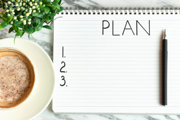 Notepad with the inscription plan and cup of coffee on marble background top view.