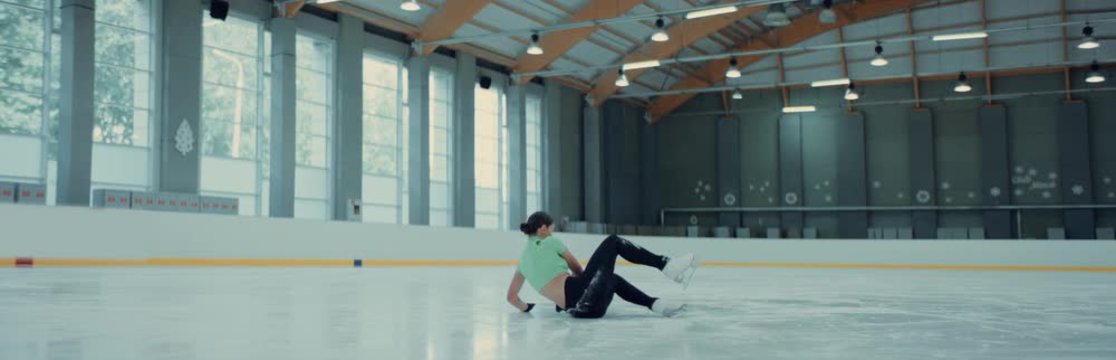 Female ice figure skater falls on ice while practicing jumps on the rink. Shot on RED cinema camera with 2x Anamorphic lens