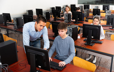 Fototapeta premium Teacher explains to male student how to use program on the computer during lesson