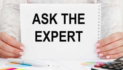 The girl holds a card with the inscription ASK THE EXPERT. A business concept.