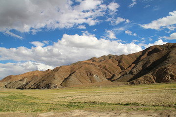 View of the mountains and barley field with dramatic sky in Tibet, China