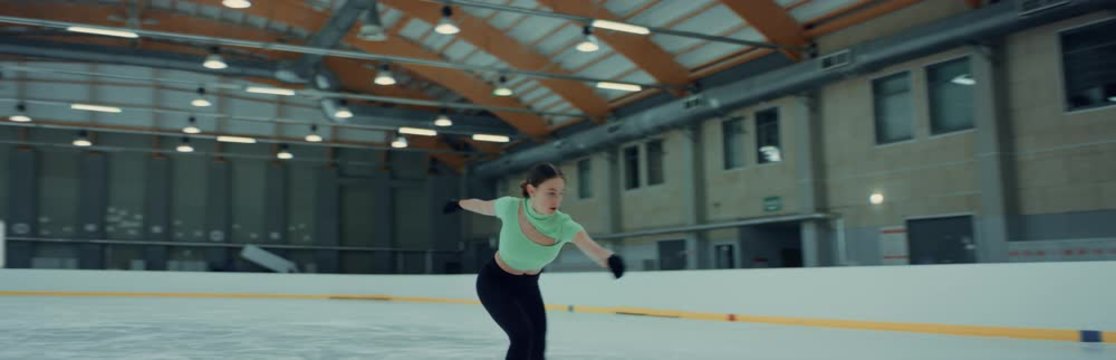 Female ice figure skater falls on ice while practicing jumps on the rink. Shot on RED cinema camera with 2x Anamorphic lens, 75 FPS slow motion