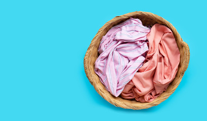 Fototapeta premium Colorful clothes in laundry basket on blue background.