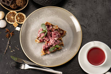 Belgian waffles with cottage cheese and strawberry jam, garnished with mint leaves for breakfast. A healthy hot dessert for tea or coffee.