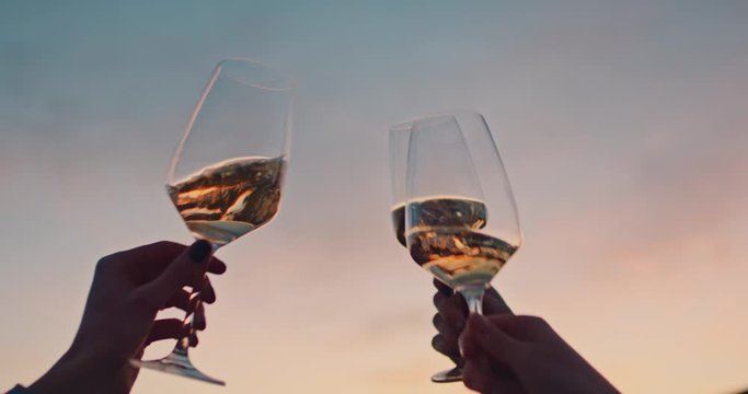 Hands of happy friends cheering celebrating holidays with wine during the epic sunset. Slow Motion.