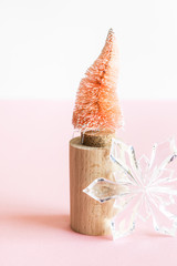 Coconut fiber orange Christmas tree on wooden stand and snowflake on pink white background, zero waste festive concept.