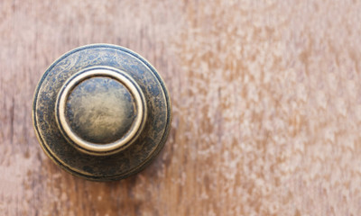 Antique metal handle on an entrance wooden door in an old building, retro concept background.