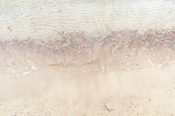 Top view Soft wave of the sea on the sandy beach with white clean foam.