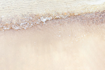 Fototapeta na wymiar Top view Soft wave of the sea on the sandy beach with white clean foam.