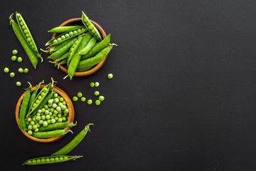 Set of green pea pods in wooden bowl on kitchen table desk