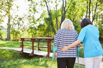 Nurse supports elderly woman while walking