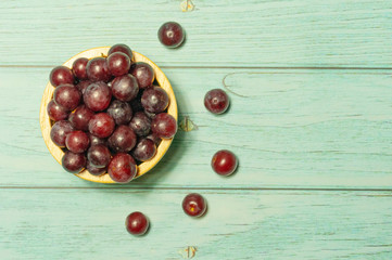 Fresh seedless red grapes in wooden bowl and lay on plank, top view.