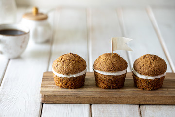 Carrot muffins with nuts and cream on a white plate. Vegan muffins. Traditional donkey pastries. Selective focus. Copy space.