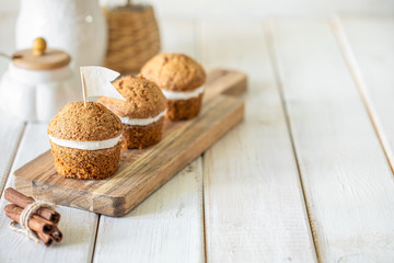 Carrot muffins with nuts and cream on a white plate. Vegan muffins. Traditional donkey pastries. Selective focus. Copy space.