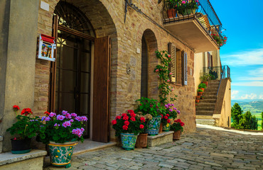 Fototapeta na wymiar Flowery entrance and street view in Tuscany, Pienza, Italy
