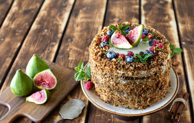 Carrot cake decorated with berries and figs on a wooden background. Traditional donkey pastries. Copy space.