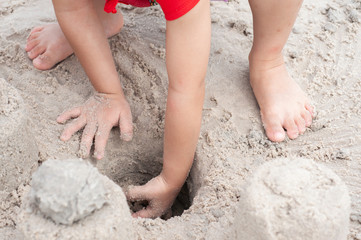 Obraz na płótnie Canvas Unidentified children play sand castle on beach in summer season.