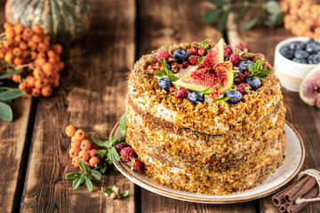 Carrot cake decorated with berries and figs on a wooden background. Traditional donkey pastries.