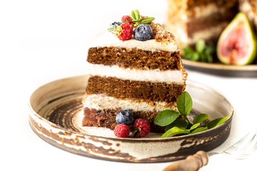 A piece of carrot cake decorated with berries and figs on a white plate. Traditional donkey pastries