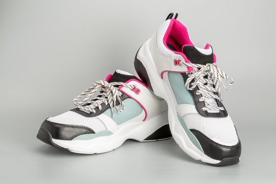 Weisse Damen-Sneaker mit hellblauen und rosaroten Akzenten. Mit grauem Hintergrund.