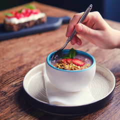Woman eating fruit dessert with a spoon in a summer cafe, close up