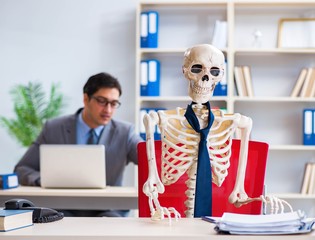 Businessman working with skeleton in office