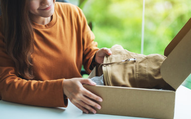 A woman receiving and opening a postal parcel box of clothing at home for delivery and online shopping concept