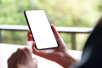 Mockup image of a woman holding mobile phone with blank white desktop screen