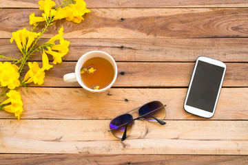mobile phone ,sunglasses and hot tea of lifestyle woman relax summer with yellow flowers...