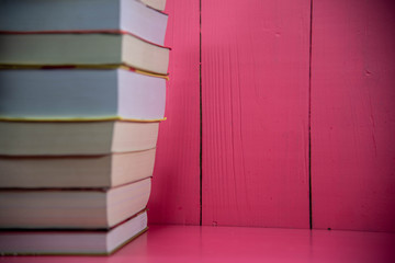 Stack of paper books on pink background