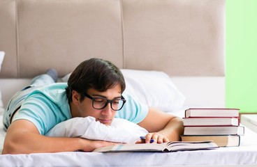 Student preparing for exams at home in bedroom lying on the bed