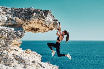 Rock climbing. Sport. Active lifestyle. Athlete woman hangs on sharp cliff. Seascape. Outdoors...