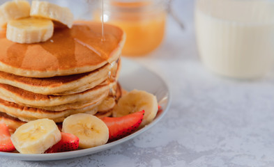 A stack of American pancakes is sprinkled with agave syrup or honey. Gray background, close-up. Copy space
