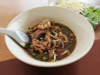 Fine cut white rice noodle thicken soup with sliced pork, sliced pork liver, fine cut morning glory, sprouts and culantro or Vietnamese coriander.  Thai boat noodle soup.  Selective focus.