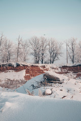 Snow-covered clay quarry in front of a fabulous winter forest.