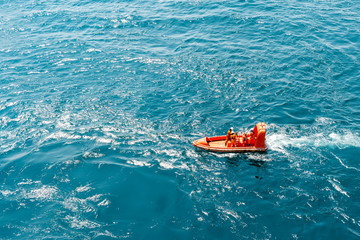 Marine crews of a pipelay barge maneuvering a light rescue craft or boat while performing man...