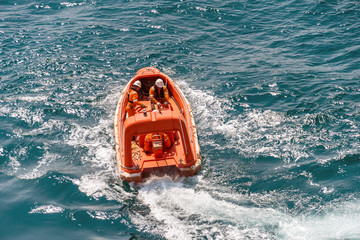 Marine crews of a pipelay barge maneuvering a light rescue craft or boat while performing man...