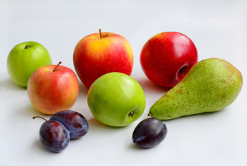 Red and green apples, pear and plums on a white background