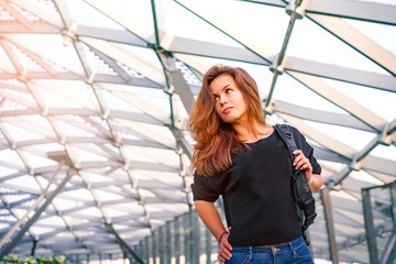 Portrait of a young woman in a black jacket in a business center with a glass ceiling in the form of a honeycomb