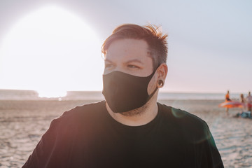 Hombre joven tocando el ukelele en la playa bajo la luz del sol durante la puesta de sol con una...